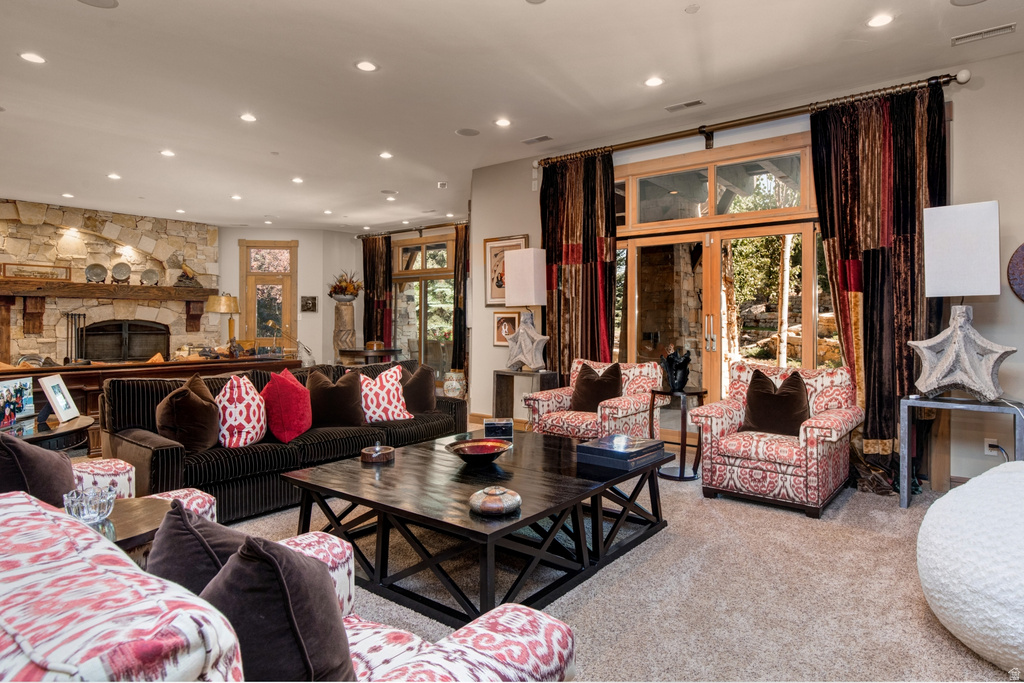 Spacious living area featuring a stone fireplace with a substantial wood mantelpiece, recessed lighting, and wood-finish French doors