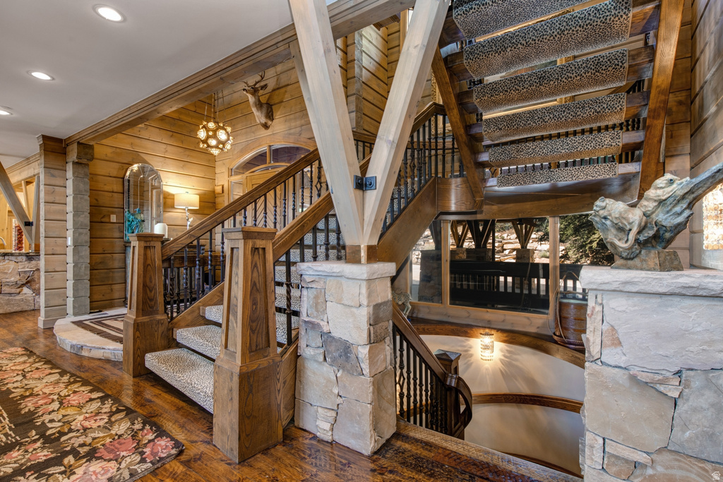 Multi-level staircase featuring wood-finish flooring, stone accents, and wrought iron balusters