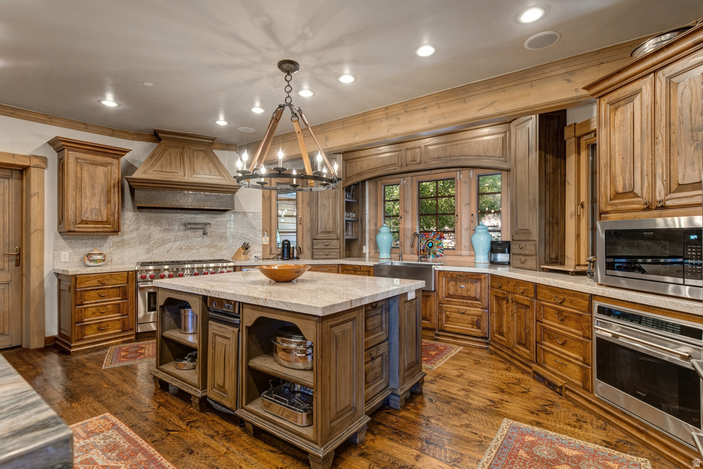 Gourmet kitchen featuring a large central island with light-toned countertop, extensive wood cabinetry, and wood-finish flooring
