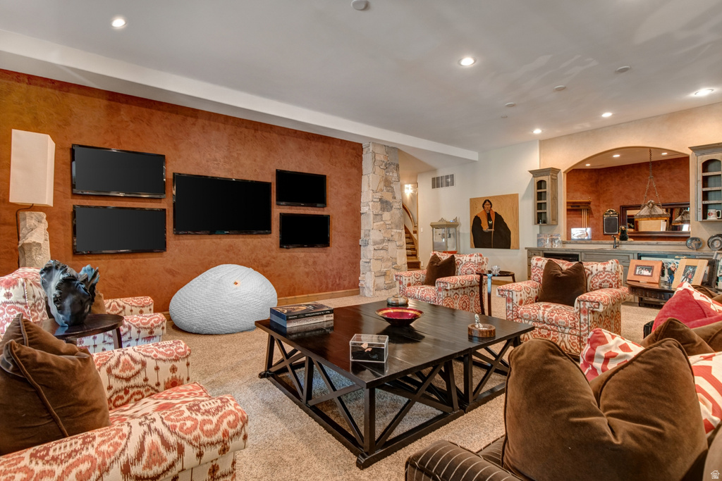 Spacious entertainment area featuring a multi-screen media wall, recessed lighting, and a substantial dark wood-finish coffee table