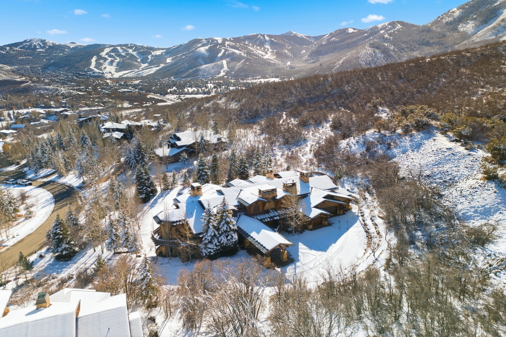 Expansive property featuring a multi-level structure with numerous chimneys, set against a mountainous backdrop