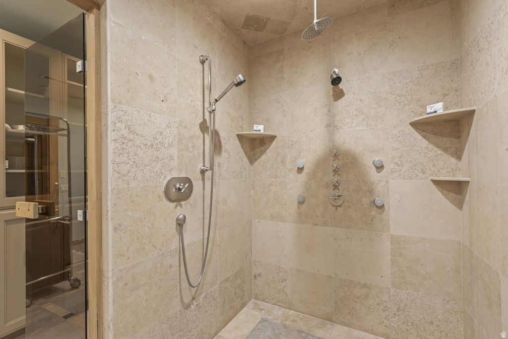 Stone-tiled shower featuring a ceiling-mounted rainfall showerhead, handheld shower fixture, and multiple body jets