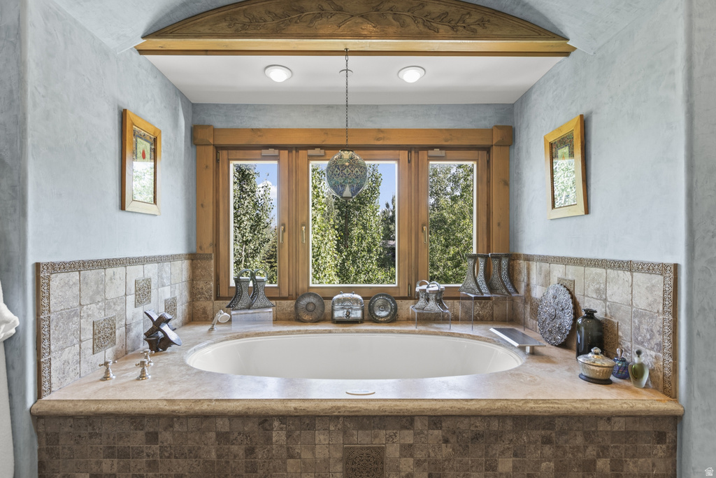 Built-in soaking tub with a stone surround, integrated deck-mounted fixtures, and a tiled base