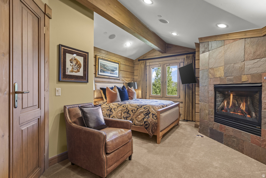 Stone-clad fireplace with a gas insert, vaulted ceilings with exposed wood beams, wood-paneled walls, and recessed lighting