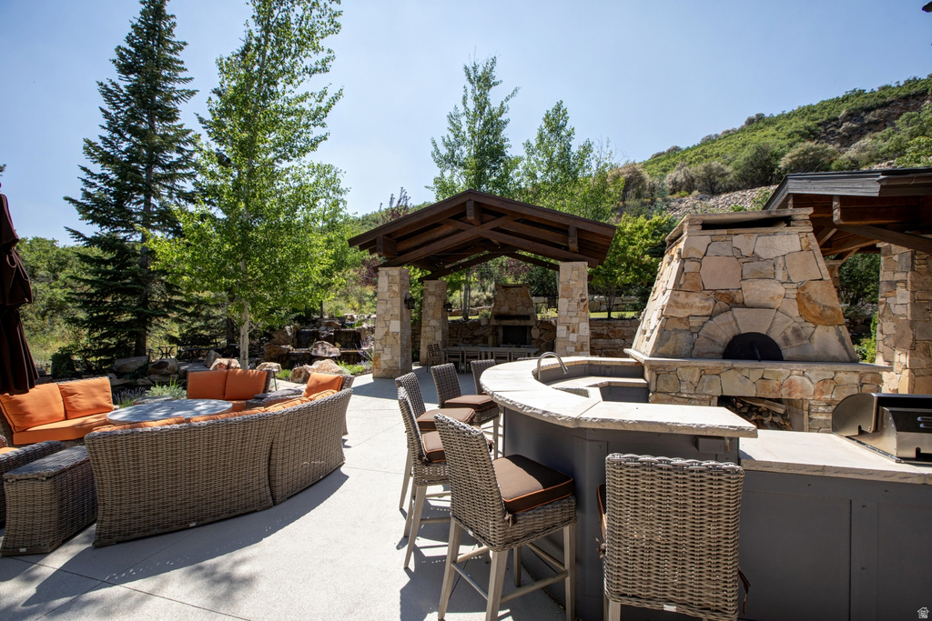 Expansive outdoor entertaining area featuring a stone pizza oven, built-in grill, and curved counter bar with a sink