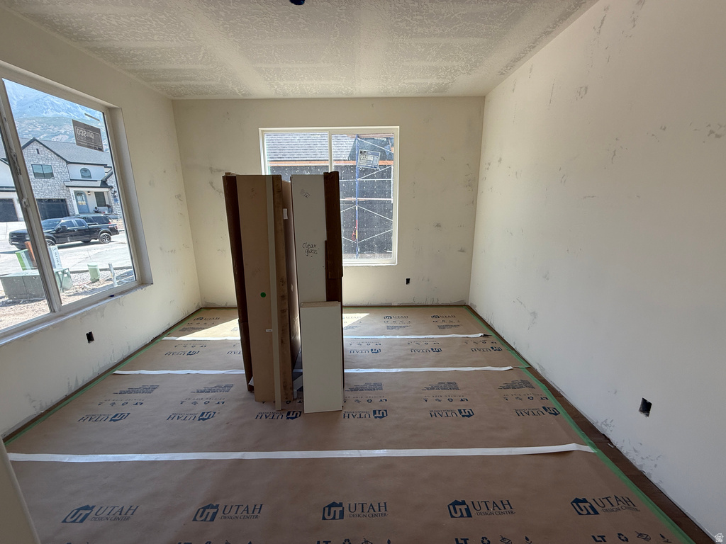 Spacious room featuring multiple windows, neutral wall tones, and a textured ceiling