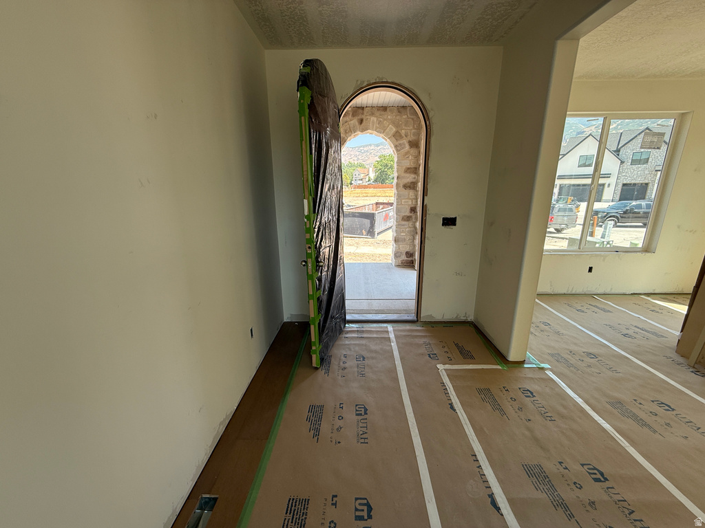Welcoming entryway featuring an arched doorway with transom window, neutral wall finishes, and wood-finish flooring throughout