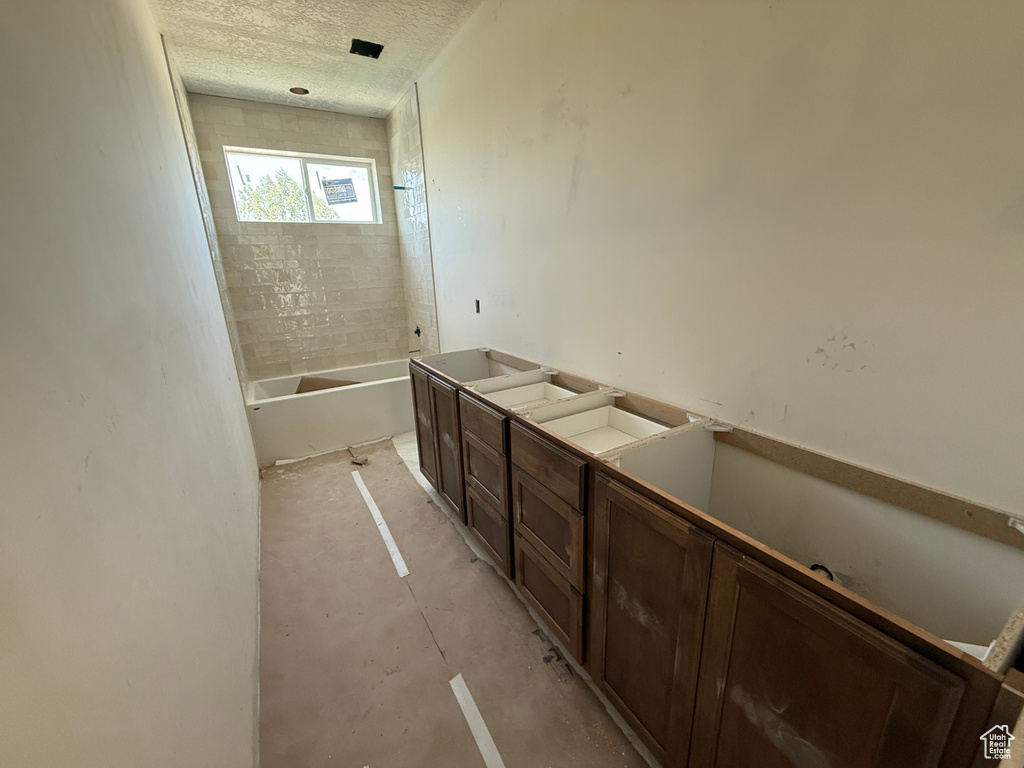 Primary Bathroom Under Renovation featuring substantial wood cabinetry, ceramic tile shower enclosure with frameless glass panel, and abundant counter space