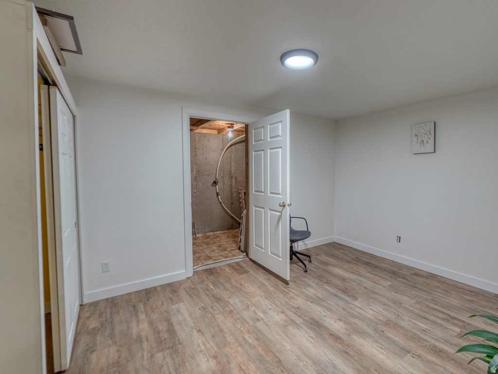 Room featuring wood-finish flooring, white baseboards, and a contemporary ceiling light fixture