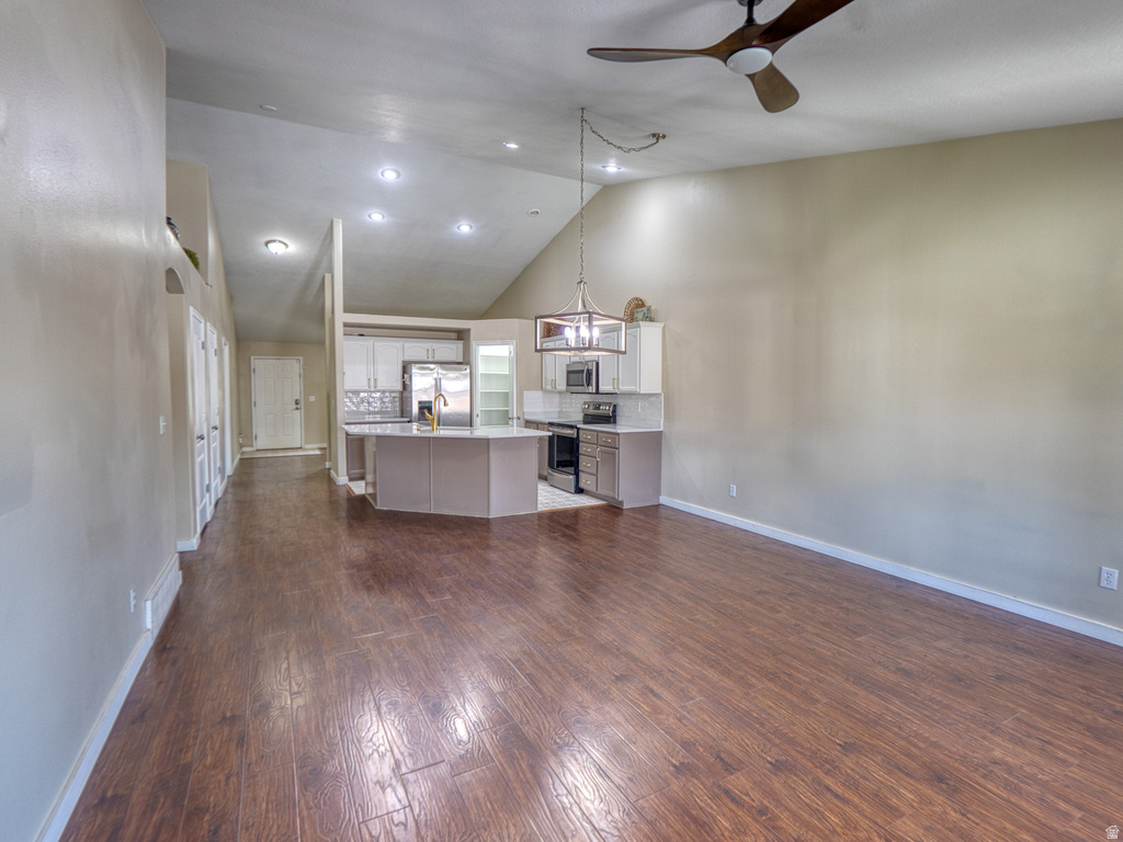 Open-concept living space featuring vaulted ceilings, wood-finish flooring, and a contemporary ceiling fan