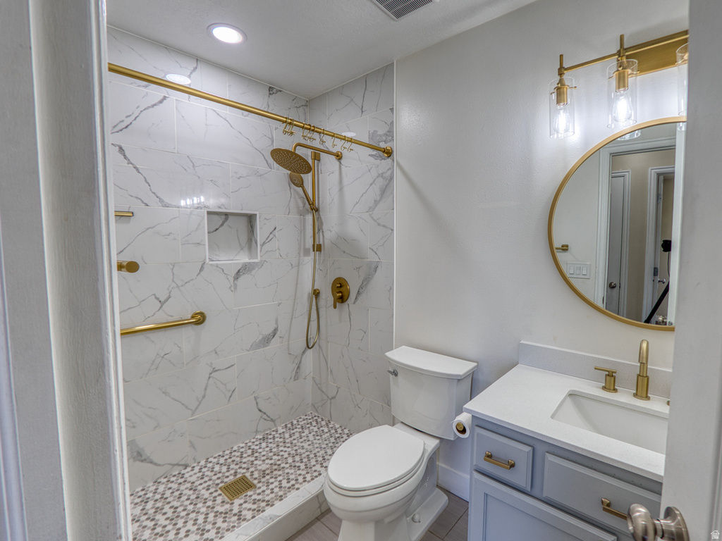 Bathroom featuring a walk-in shower with large format marble-look tile, a mosaic tile shower pan, and gold-finish fixtures