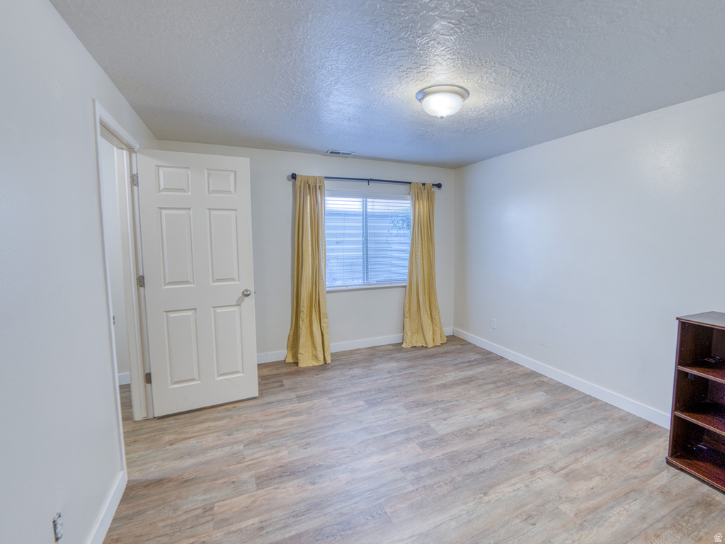 Neutral tone wall finish, wood-finish flooring, white trim, window with horizontal blinds, and a flush mount ceiling light fixture