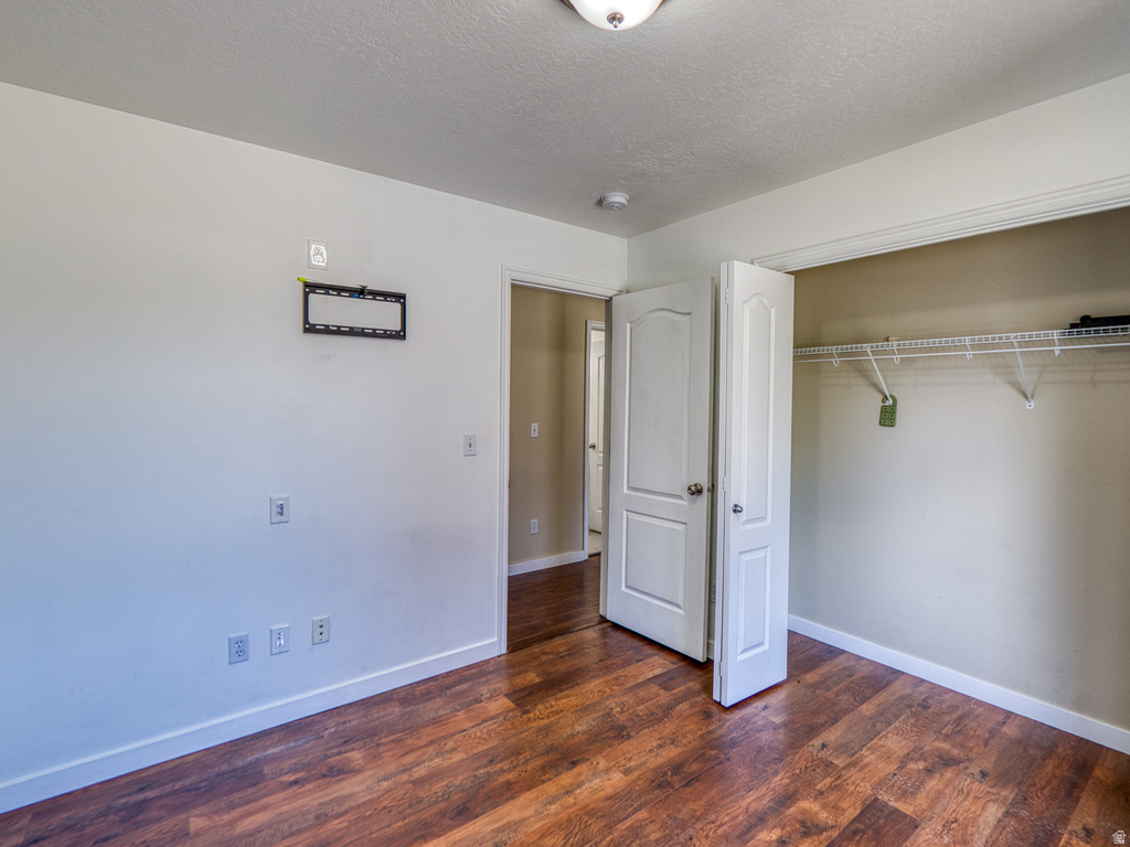 Room featuring rich wood-finish flooring, white baseboards, and a neutral wall color