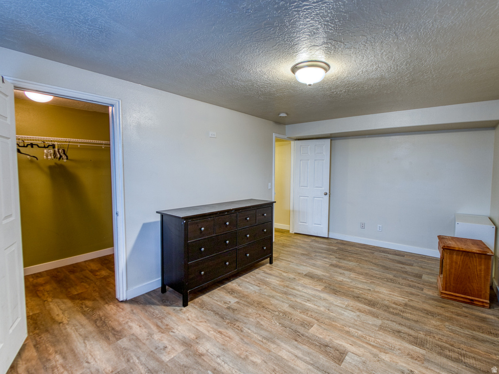 Spacious room featuring wood-finish flooring, a ceiling-mounted light fixture, and a built-in closet with shelving and hanging rods