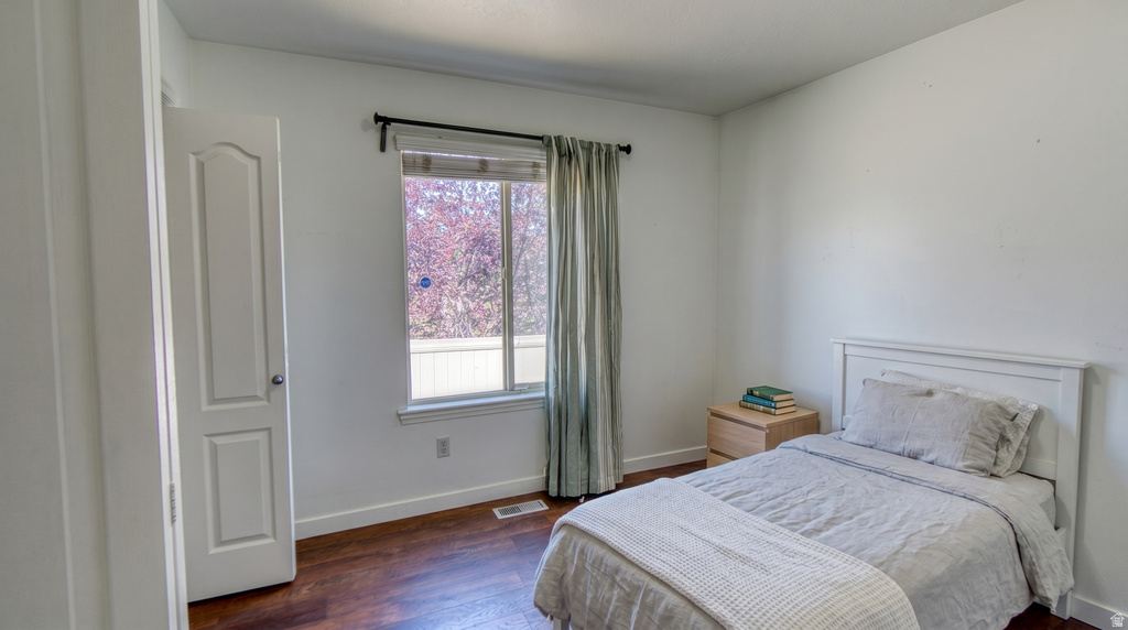 Spacious room featuring wood-finish flooring, white baseboards, and a window with a dark rod