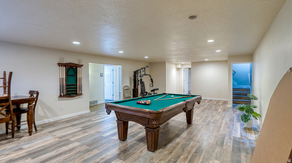 Spacious recreation area featuring wood-finish flooring, recessed lighting, and a built-in cue rack