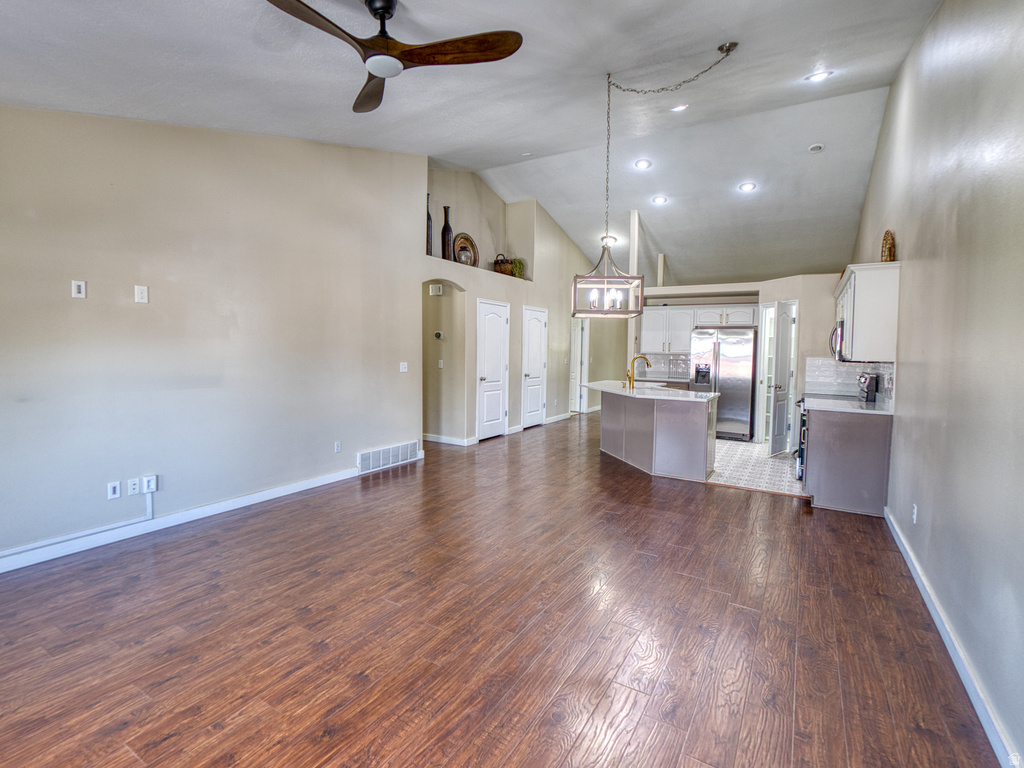 Open-concept living area featuring wood-finish flooring, vaulted ceilings, and a ceiling fan with integrated lighting