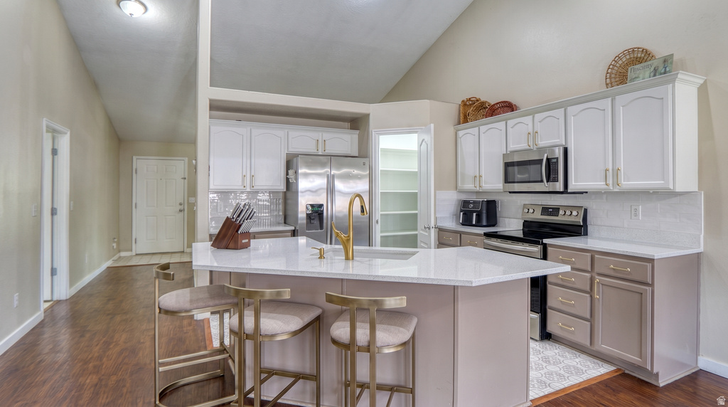 Kitchen featuring a peninsula island with solid surface countertop, white upper cabinetry, complementary lower cabinetry, and stainless steel appliances