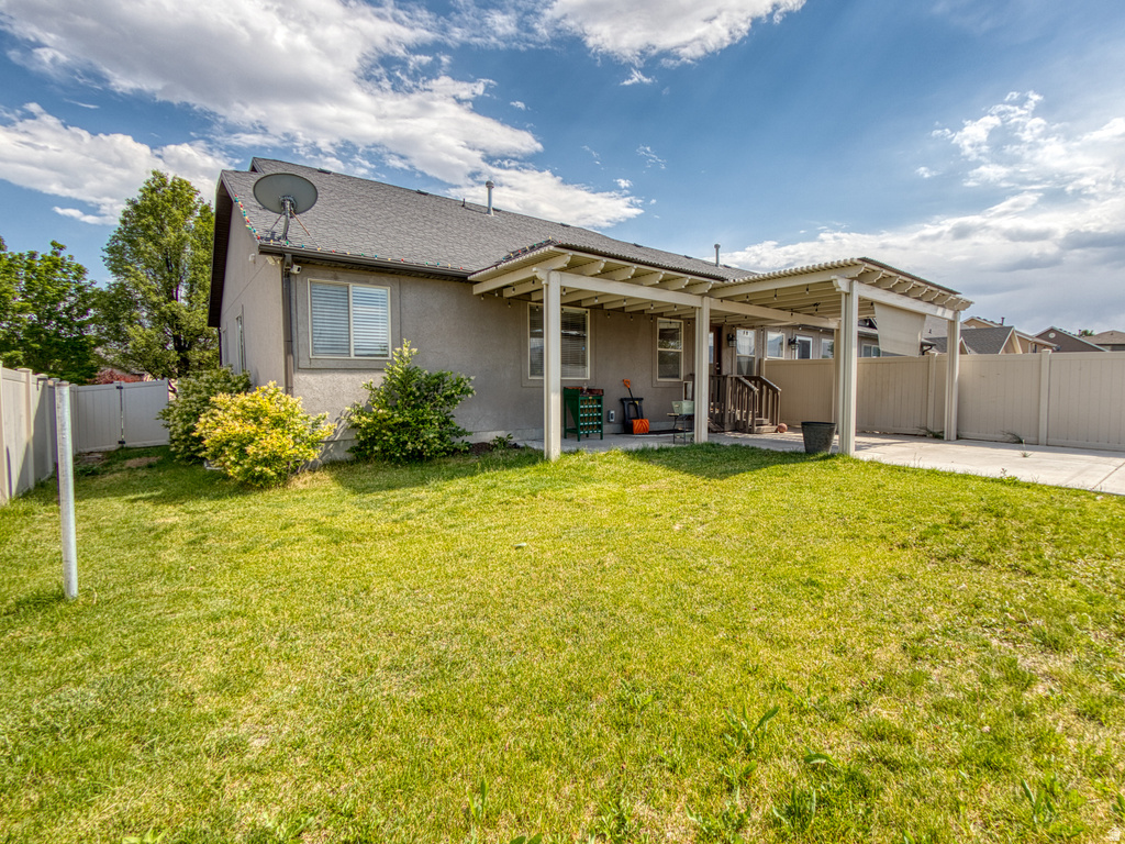 Expansive rear yard featuring a covered patio, concrete slab, and privacy fencing