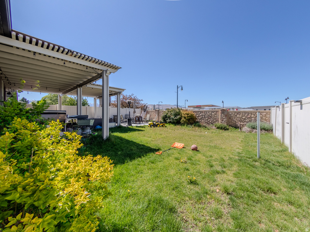 Spacious backyard featuring a covered patio, extensive lawn area, and privacy fencing