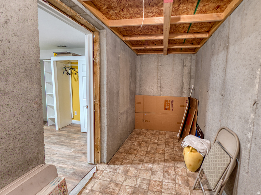 Unfinished basement area featuring concrete walls and an exposed wood-finish ceiling