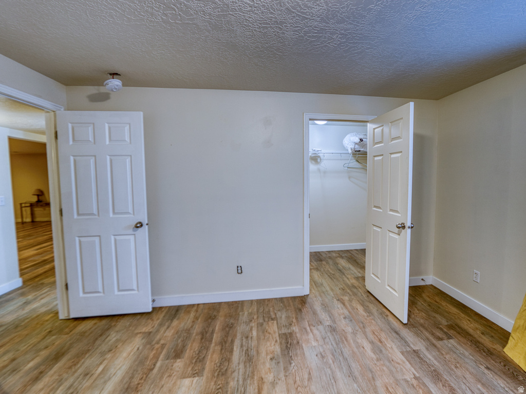 Interior room featuring wood-finish flooring, light-toned walls, and a textured ceiling