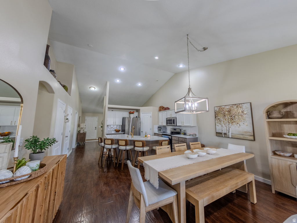 Open-concept living space featuring wood-finish flooring, vaulted ceilings, recessed lighting, and a modern kitchen with a large island and stainless steel appliances