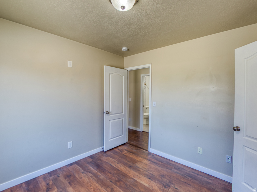 Interior room with wood-finish flooring, neutral wall paint, white trim, and a semi-flush ceiling light fixture