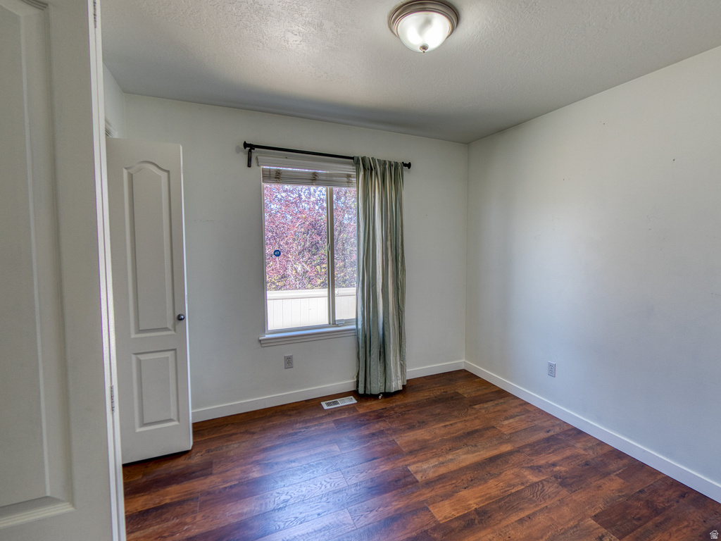 Room featuring wood-finish flooring, white baseboards, and a single window with a dark curtain rod