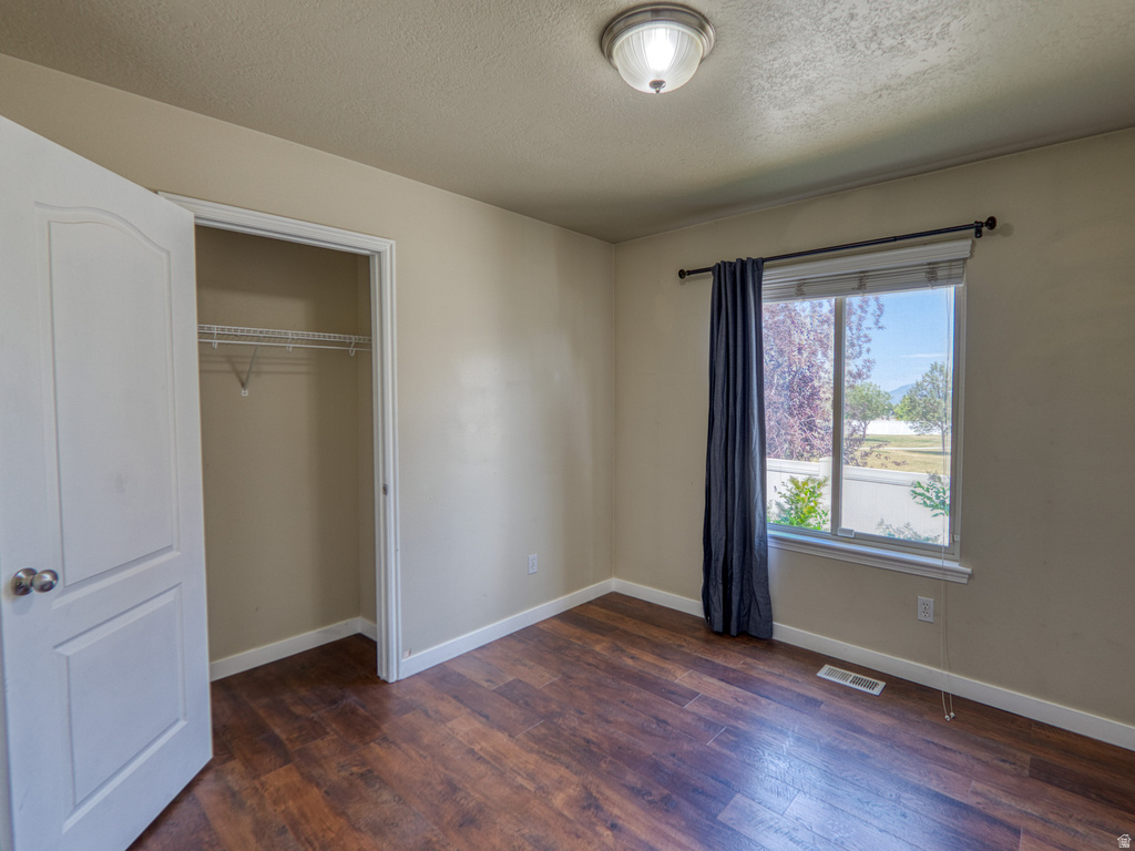 Room featuring dark wood-finish flooring, neutral wall tones, and a window with natural light