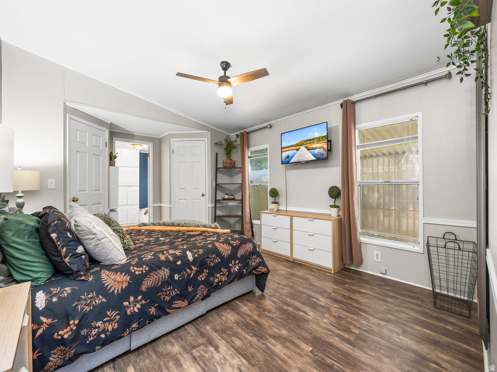 Spacious room featuring wood-finish flooring, a ceiling fan with integrated lighting, multiple windows, and a built-in shelving unit
