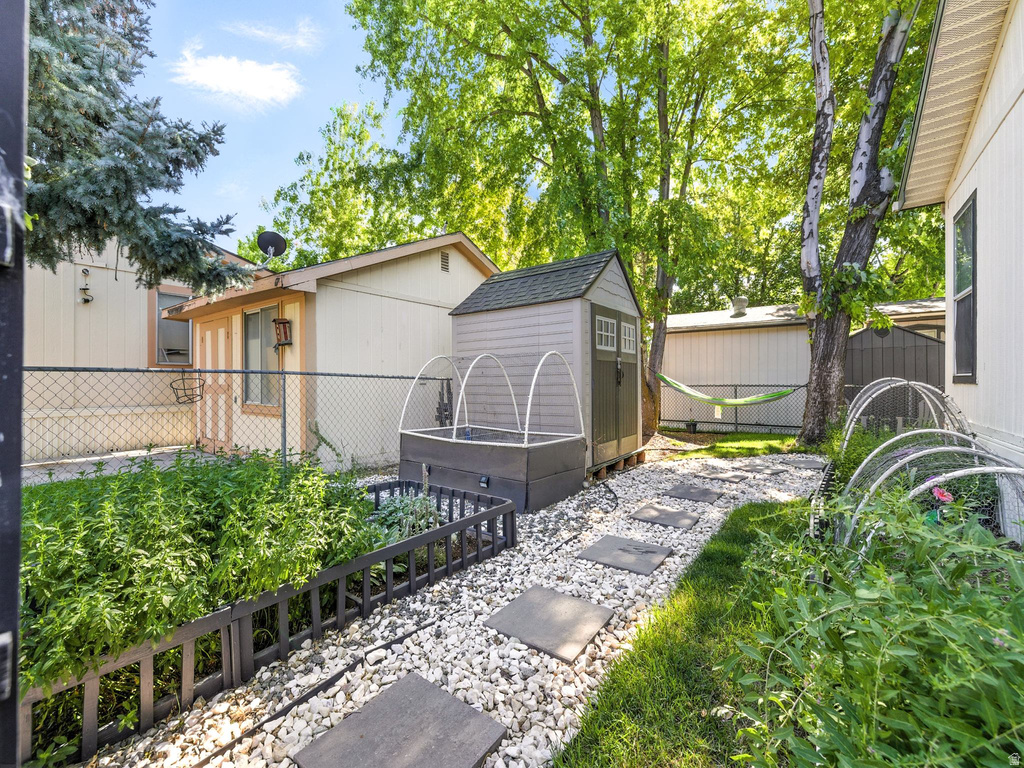 Backyard space featuring a stone walkway, raised garden beds, and a storage shed