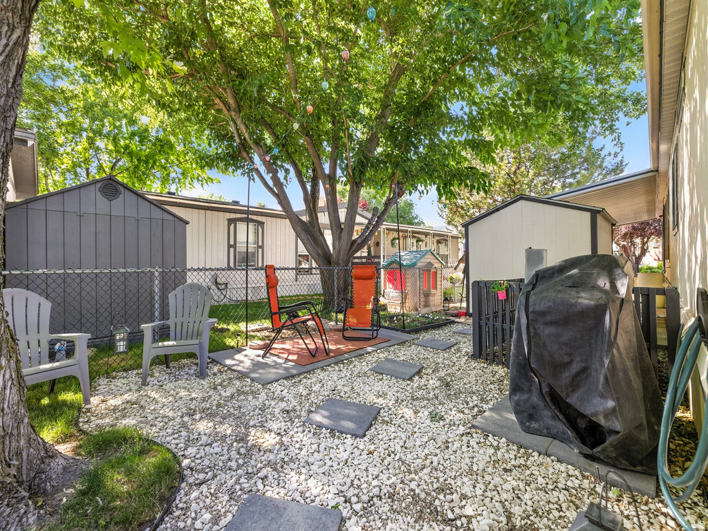 Expansive outdoor space featuring a mature shade tree, two storage sheds, and a gravel-covered ground with stepping stones