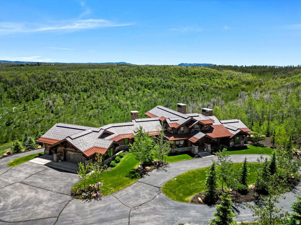 Expansive property featuring a rustic stone and wood-sided residence with multiple gables and a large paved driveway