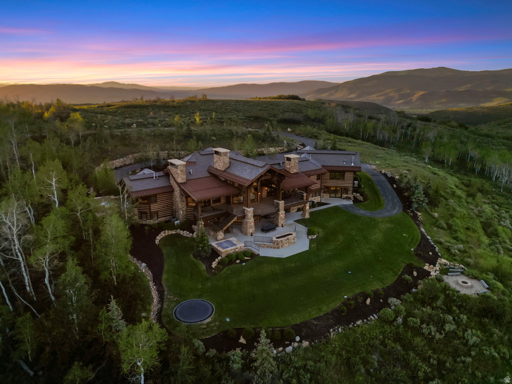 Expansive mountain estate featuring a multi-level log and stone exterior, extensive landscaping, and a manicured lawn