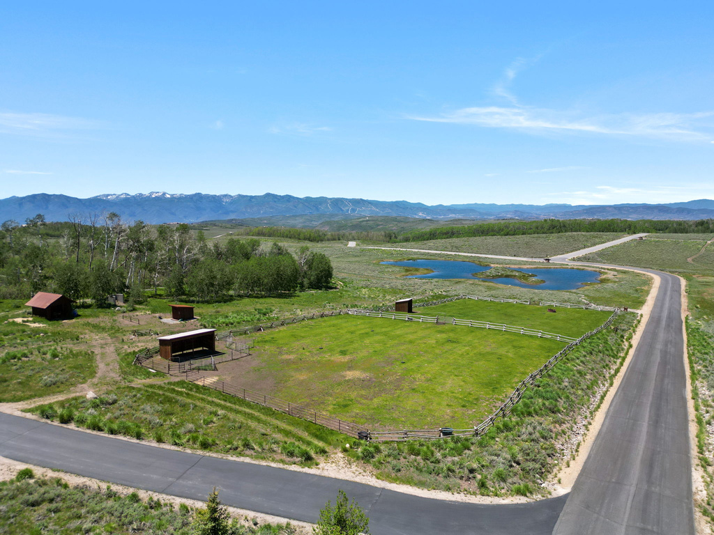 Expansive land parcel featuring a fenced green pasture, two outbuildings, and two ponds