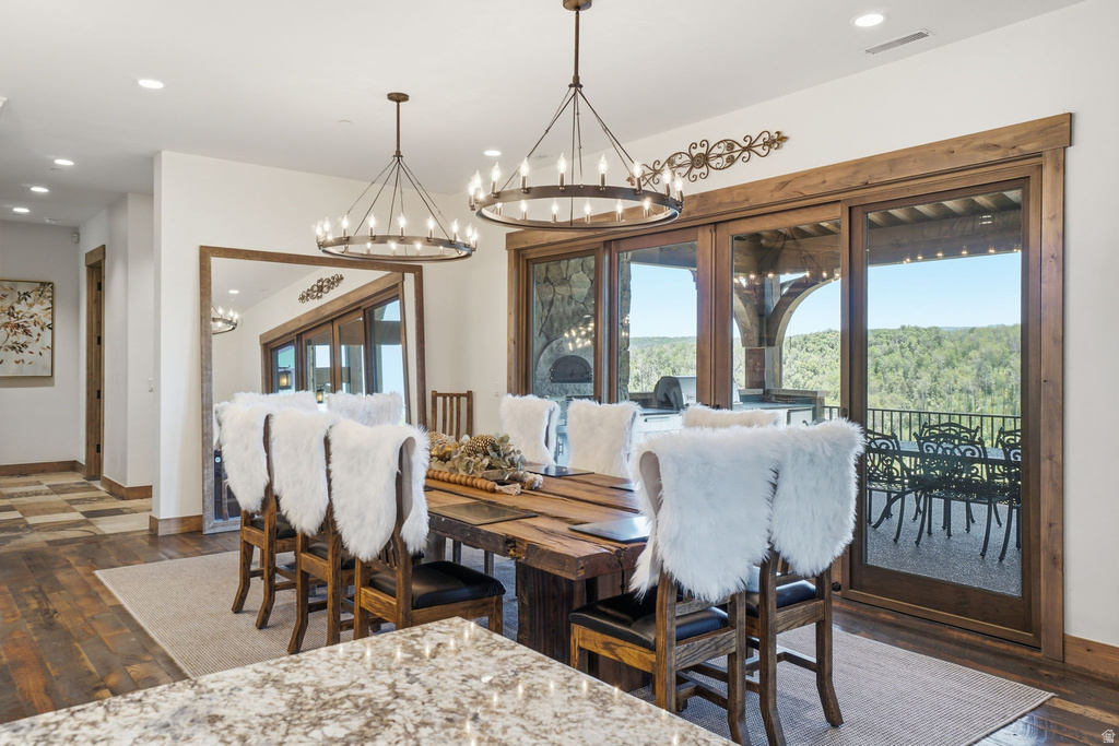 Dining area featuring two large circular chandeliers, wood-finish flooring, and a full wall of glass sliding doors with wood frames