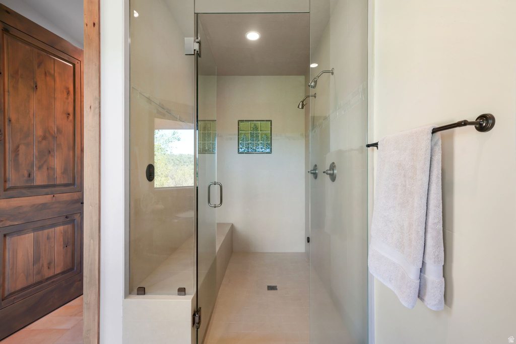 Spacious shower enclosure with clear glass panels, multiple shower heads, a built-in bench, and recessed lighting