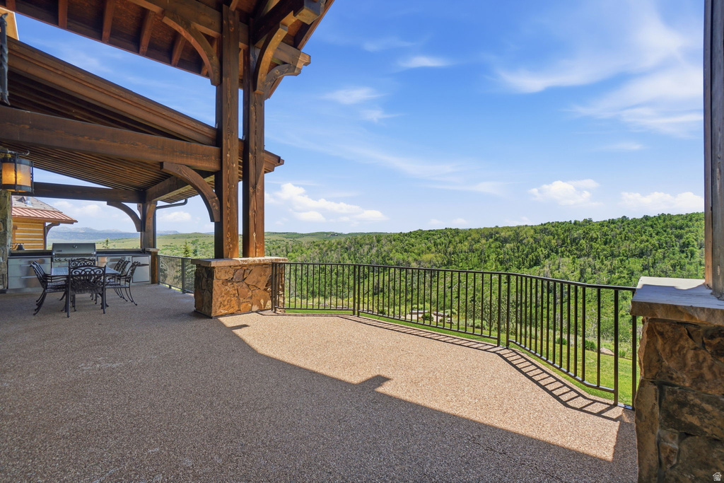 Spacious outdoor patio featuring exposed timber beams, a built-in barbecue station, and expansive natural scenery