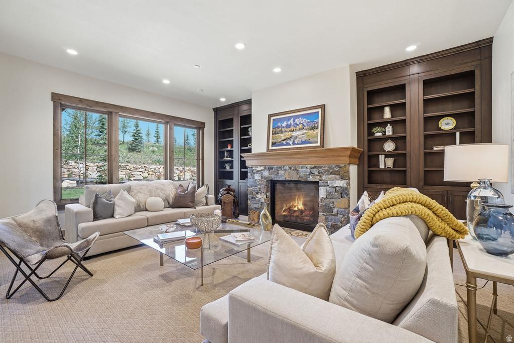 Living area featuring a stone-faced fireplace with a wood mantel, built-in dark wood shelving, and large windows with wood trim