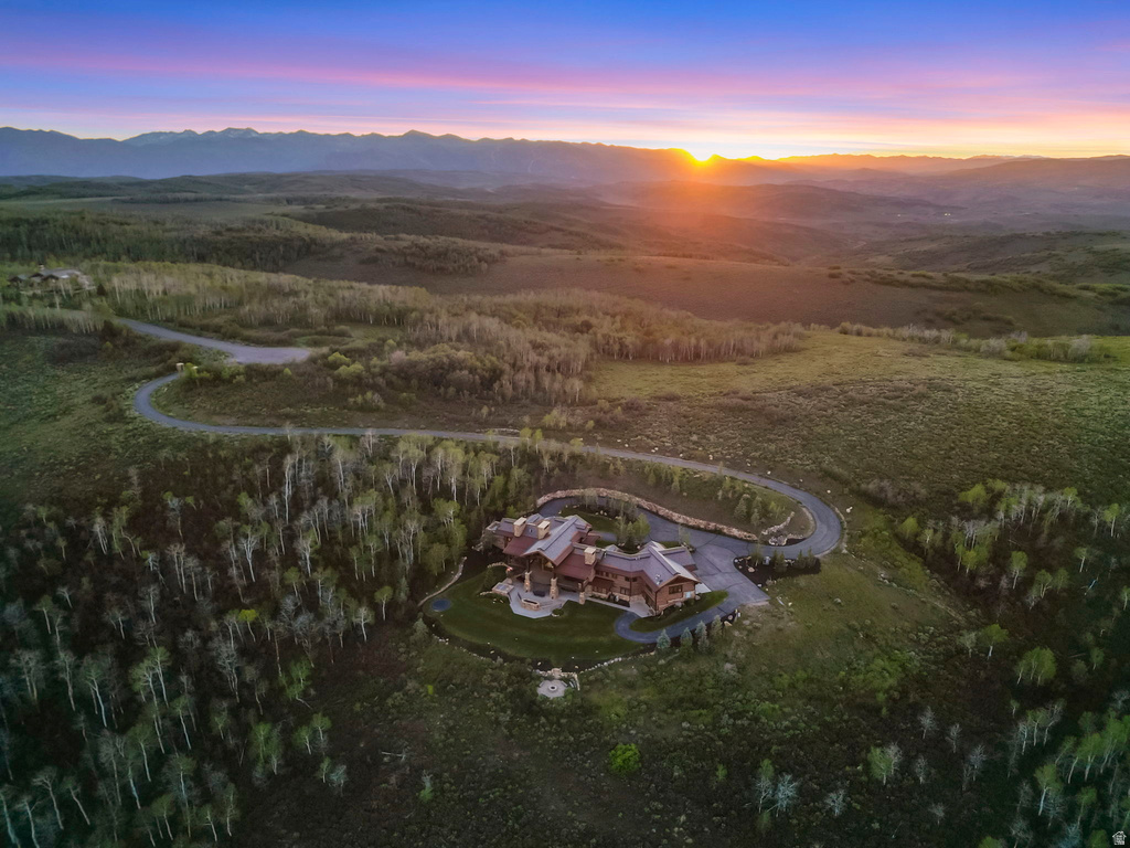 Extensive property featuring a winding driveway, mature trees, mountain backdrop, and a substantial residence with multiple gables