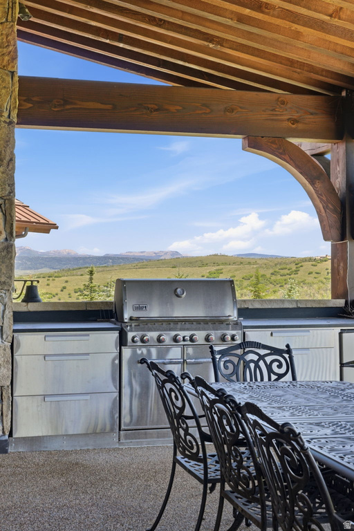 Outdoor kitchen featuring a built-in stainless steel grill, stainless steel cabinetry, and stone surround