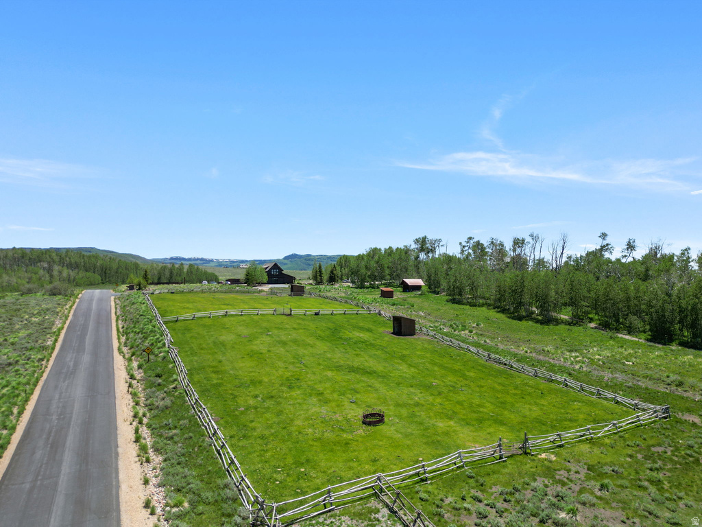 Expansive green pasture enclosed by a rustic split-rail fence, featuring a circular fire pit