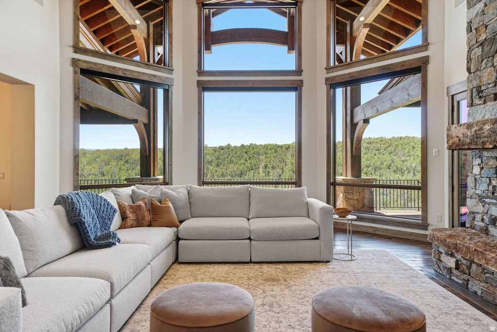 Great room featuring a floor-to-ceiling stone fireplace, wood-finish flooring, and expansive windows