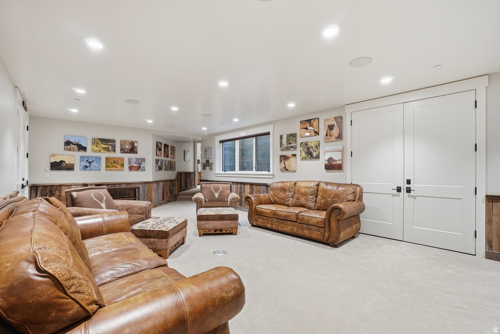 Spacious recreational room featuring recessed lighting, light-toned carpeting, and white walls with a wood-panel accent