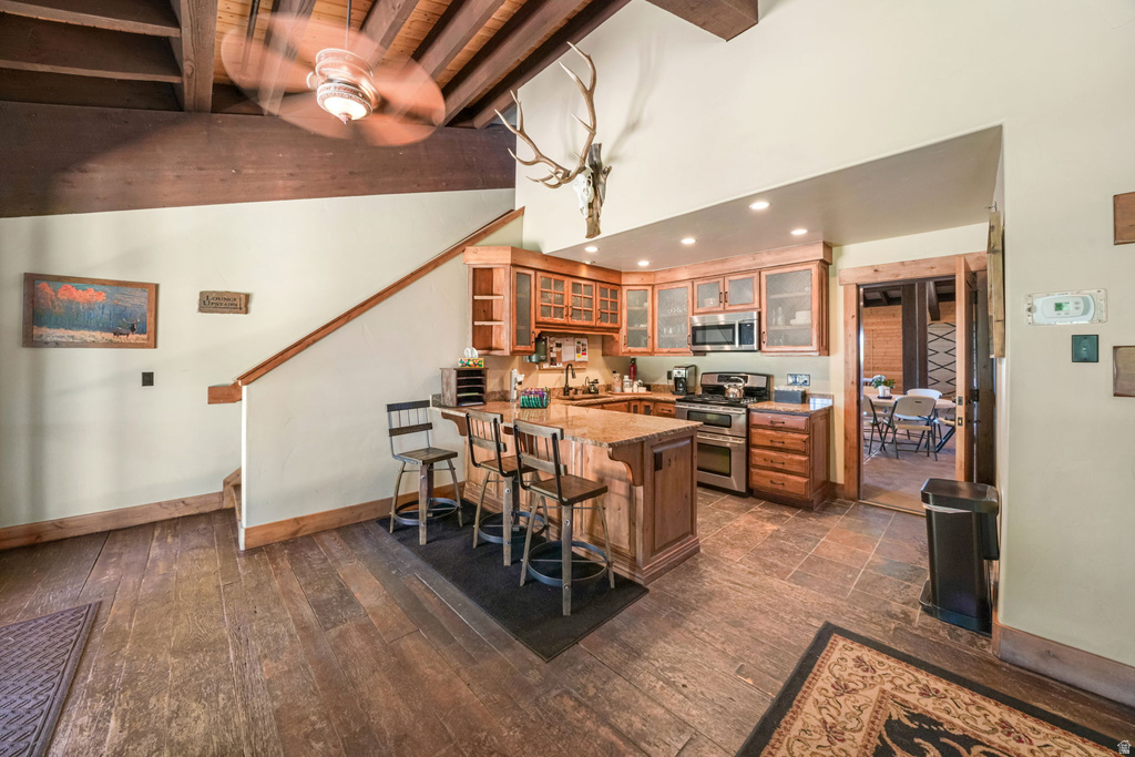Kitchen featuring recessed lighting, stainless steel appliances, wood cabinetry with glass inserts, and an island with seating