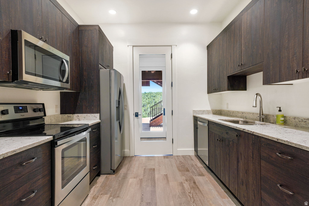 Galley-style kitchen featuring dark wood-finish cabinetry, light-toned countertops, and stainless steel appliances