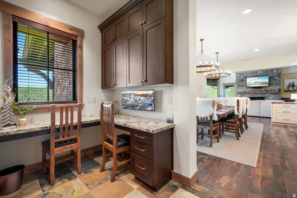 Dedicated workspace featuring dual built-in desks with stone countertops, custom wood cabinetry, and a large window