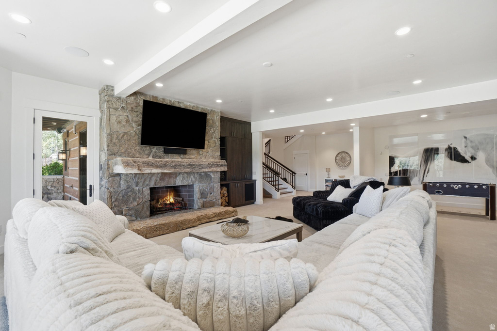 Spacious living area featuring a floor-to-ceiling stone fireplace, recessed lighting, and light-colored carpeting