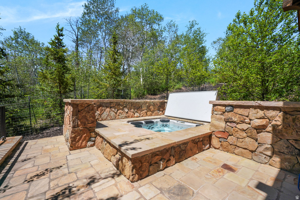 Stone patio with an integrated spa, surrounded by natural rock walls and mature trees